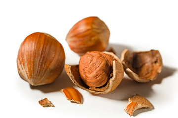 Some shelled hazelnuts with shell fragments around them, isolated on a white background