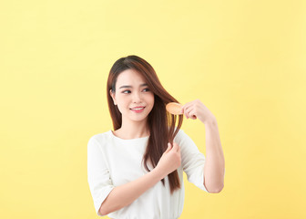 Portrait of beautiful young woman combing her hair and smiling