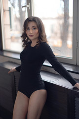  Portrait of a young girl in a black bodysuit by the window