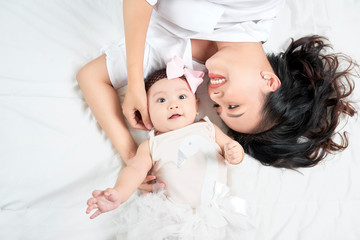 Young mother and cute baby on bed at home