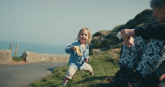 Little toddler on picnic with grandmother doing a dance