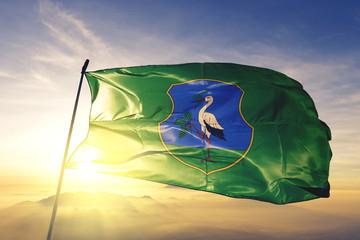 Heves county of Hungary flag waving on the top sunrise mist fog