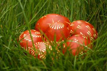 Ukrainian painted easter eggs of red color lie in the grass. Close-up
