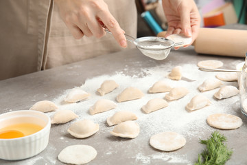 Woman cooking delicious dumplings at table, closeup