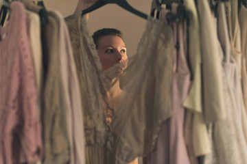  beautiful young woman choosing what to wear standing in front of her wardrobe early morning. View from inside the wardrobe