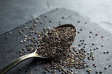 Spoon and scattered chia seeds on slate plate, closeup