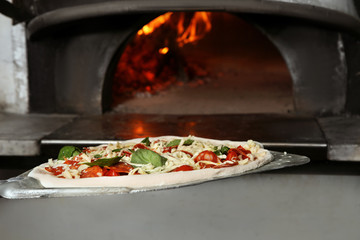 Putting traditional Italian pizza into oven in restaurant kitchen
