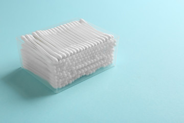 Plastic container with cotton swabs on color background. Space for text