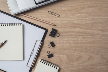 Workspace with diary or notebook and laptop, pen, pencil, metal clip on wooden background