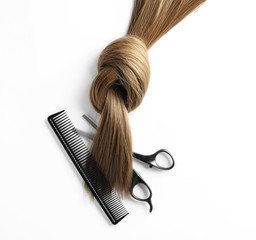 Beautiful brown hair, scissors and comb on white background, top view. Hairdresser service