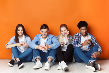 Gadget addiction. Teenagers with smartphones, orange wall