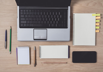 Workspace with diary or notebook and clipboard, laptop, pencil, pen, sticky notes, smart phone on wooden background