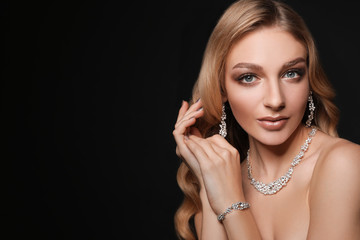 Obraz premium Beautiful young woman with elegant jewelry on dark background. Space for text