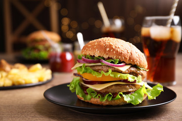 Plate with delicious hamburger on wooden table. Space for text