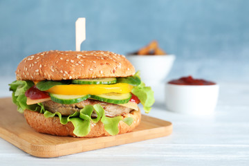 Board with delicious hamburger on table. Space for text