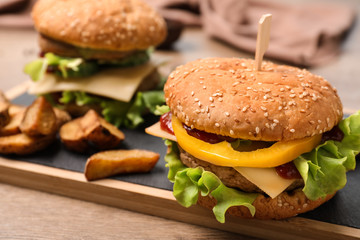 Board with delicious hamburger on table. Space for text
