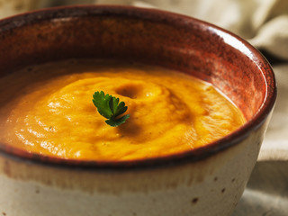 Zuppa di zucca rossa su un tavolo di cemento con prezzemolo