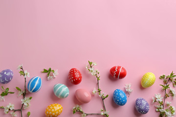 Flat lay composition with painted Easter eggs and blossoming branches on color background, space for text