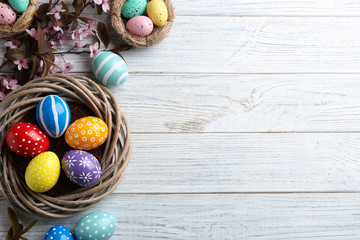 Flat lay composition with painted Easter eggs and blossoming branches on wooden background. Space for text