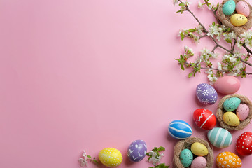 Flat lay composition with painted Easter eggs and blossoming branches on color background, space for text