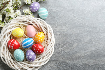 Flat lay composition with painted Easter eggs and blossoming branches on color background. Space for text