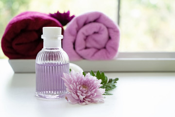 Obraz na płótnie Canvas The bottle of massge oil put beside pink flower,aromagheraphy product of spa therapy on background