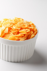 White cup with golden corn flakes isolated on white background. View from above. Delicious and healthy breakfast