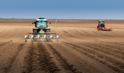Obraz premium Farmer with tractor seeding sowing crops at agricultural field