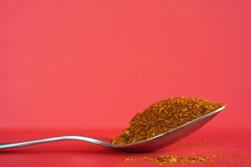 Spoonful of Dry Ground Peppers - Chili - on red background