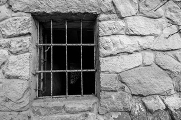 Metal grid on old abandoned stone house window close up shot in black and white.