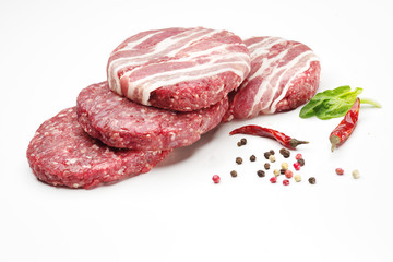 Raw meat patties with spices for burgers on a white background.