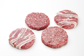 Raw meat patties for burgers on a white background.