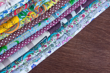 stack of multicolored fabrics on a wooden table