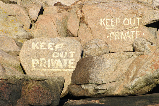 Keep Out Sign Painted on Boulders at the Seashore