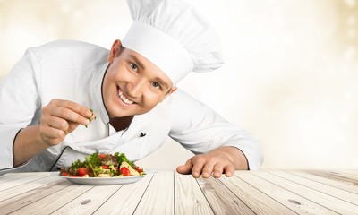 Portrait of a male chef cook preparing salad  isolated on  background