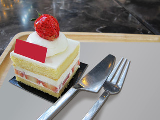 Strawberry cake placed on a wooden tray with fork and knife