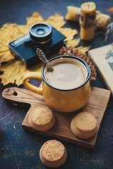 Yellow mug with autumn leaves, a book and candles. The concept of comfort and warmth.