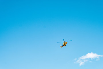 Fototapeta na wymiar A yellow helicopter flying in the blue sky.