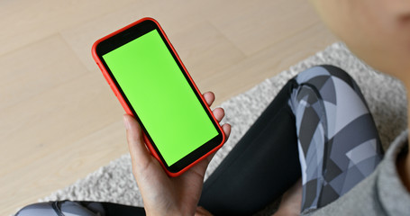 Woman hold with cellphone with green screen at home