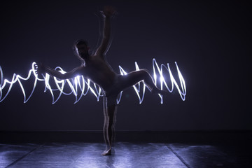 Modern Dance performer dancing with a neon blue light while making gracious moves and spectacular...