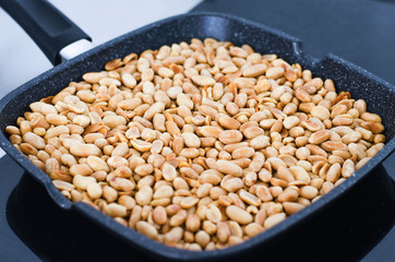 Frying on the stove in a black pan peanuts.