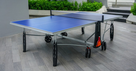 Blue table tennis table on wooden floor. Ping-Pong table