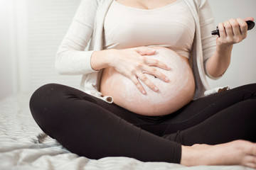 Close up of Pregnant woman applying cream at her belly