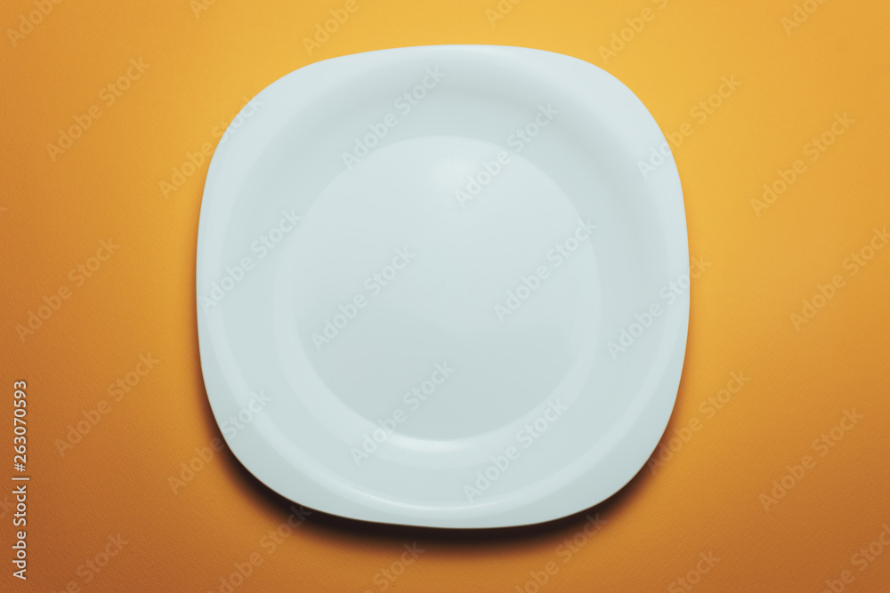 Poster white bowl and a fork with a spoon on an orange background