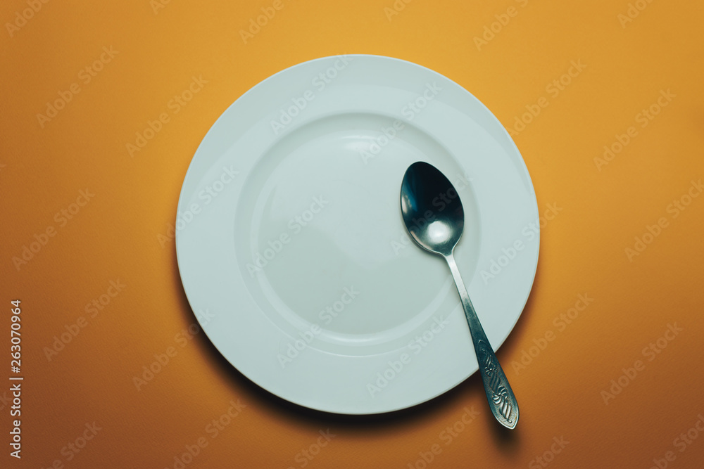 Poster white bowl and a fork with a spoon on an orange background