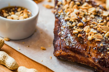 Close up board with pork ribs grilled with BBQ sauce and peanuts
