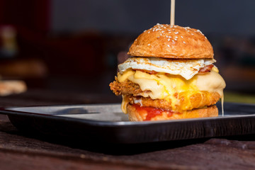 Close up tall tasty burger with cheese and egg served on tray