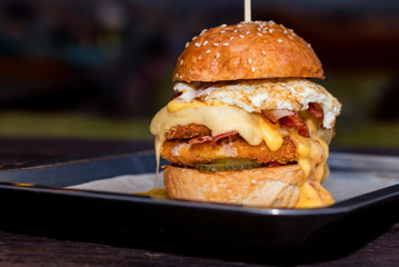 Close up tall tasty burger with cheese and egg served on tray