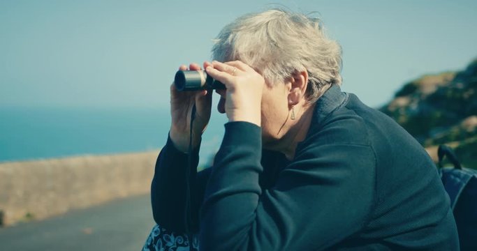Senior woman looking at the sea with monocular