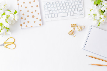 Flat lay blogger or freelancer workspace with a notebook, keyboard and white spring flowers on a...